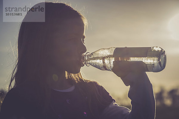 Mädchen-Trinkwasser aus einer Wasserflasche bei Gegenlicht