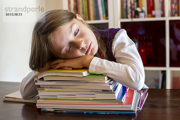 Mädchen schläft auf einem Stapel Schulbücher