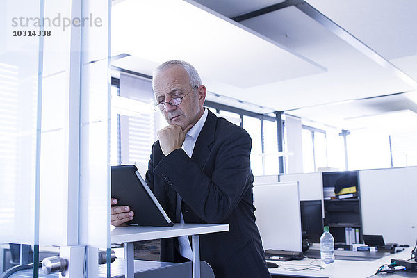 Geschäftsmann im Großraumbüro mit digitalem Tablett