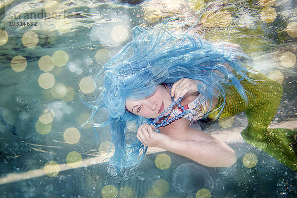 Junge Frau in der Verkleidung von Arielle  der kleinen Meerjungfrau  blaue Haare  unter Wasser