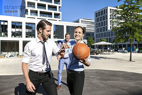 Gruppe von Geschäftsleuten  die im Freien Basketball spielen