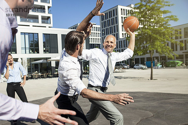 Gruppe von Geschäftsleuten  die im Freien Basketball spielen