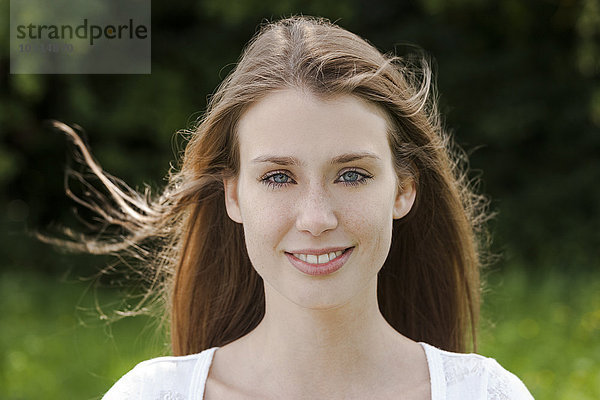 Porträt einer lächelnden jungen Frau mit wehendem Haar