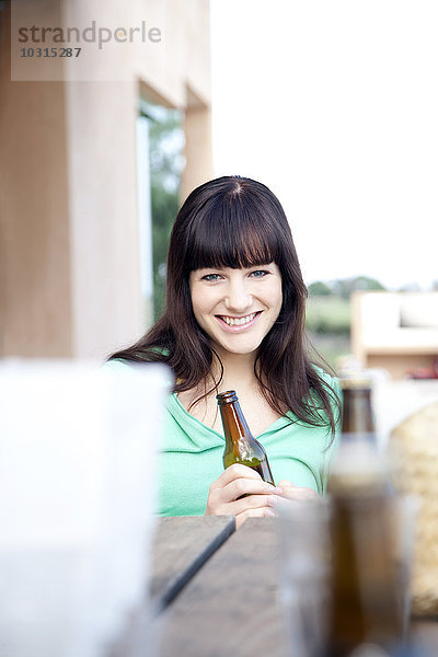 Fröhliche junge Frau beim Biertrinken