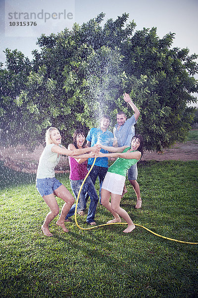 Fünf Freunde planschen mit Wasser im Garten