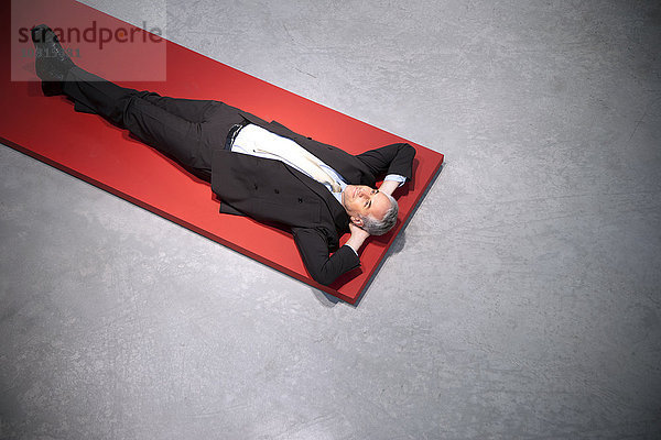 Entspannter Geschäftsmann auf dem Boden liegend