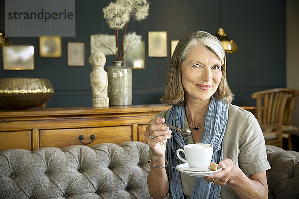 Lächelnde Seniorin im Aufenthaltsraum bei einer Tasse Kaffee