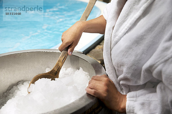 Frau mit Holzlöffel im Eiskübel im Spa