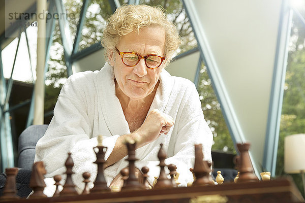 Senior im Bademantel beim Schachspielen
