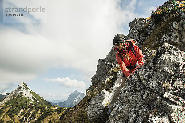 Österreich  Tirol  Tannheimer Tal  junge Frau beim Wandern auf Felsen