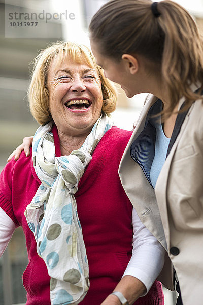 Porträt einer lachenden Seniorin  die mit ihrer Enkelin kommuniziert.
