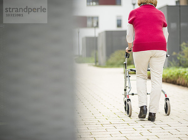 Seniorin beim Gehen mit Rollator  Rückansicht