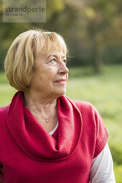 Porträt einer blonden Seniorin mit rotem Pullover