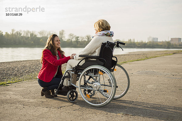 Erwachsene Enkelin  die ihrer Großmutter im Rollstuhl assistiert