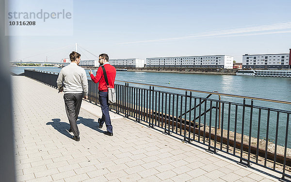 Zwei junge Geschäftsleute  die am Flussufer spazieren gehen.
