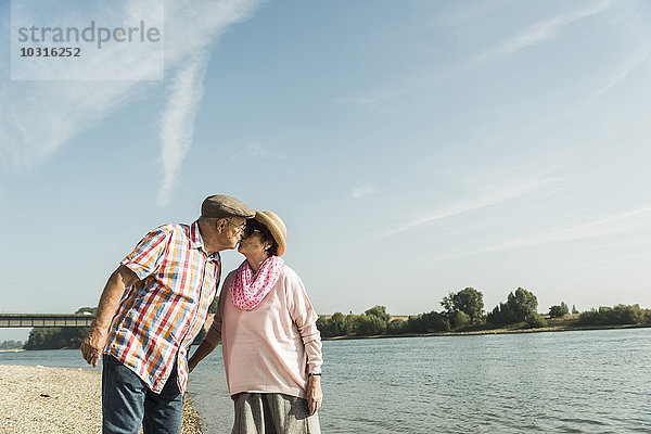 Deutschland  Ludwigshafen  küssendes Seniorenpaar am Flussufer
