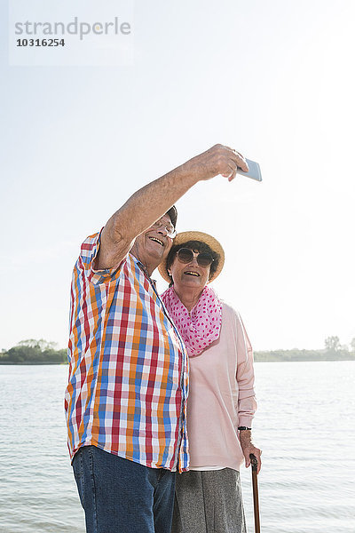 Seniorenpaar mit einem Selfie am Flussufer