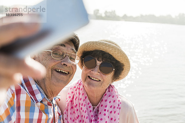 Seniorenpaar mit einem Selfie am Flussufer