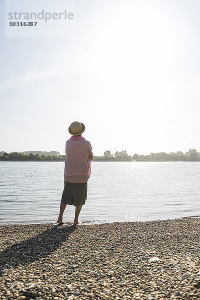 Rückansicht der Seniorin beim Entspannen am Flussufer