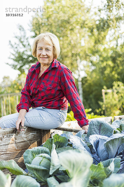 Lächelnde Seniorin im Gemüsebeet
