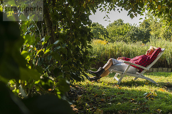 Seniorin entspannt im Gartenstuhl
