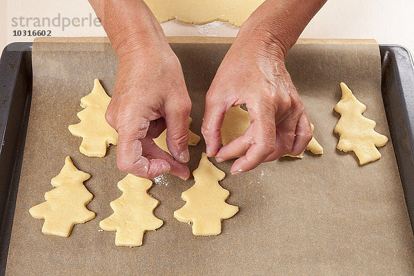 Frau legt Weihnachtsbaumplätzchen auf das Backblech