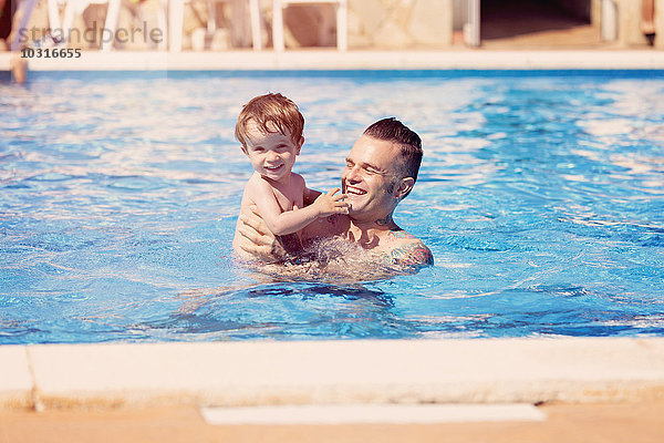 Tätowierter Mann mit seinem kleinen Sohn im Schwimmbad