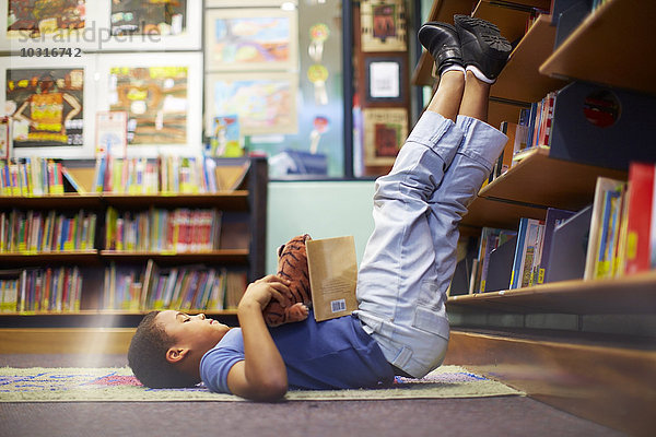 Junge auf dem Boden liegend in der Bibliothek