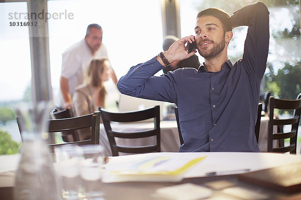 Portrait eines Geschäftsmannes beim Telefonieren mit dem Smartphone im Restaurant