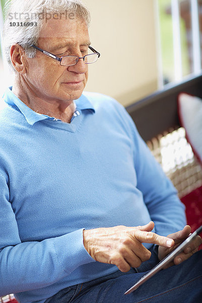 Senior Mann mit digitalem Tablett zu Hause