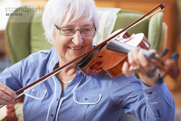 Seniorin zu Hause beim Geigenspiel