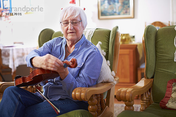 Seniorin zu Hause beim Stimmen der Geige