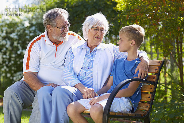 Großeltern und Enkel auf der Parkbank sitzend