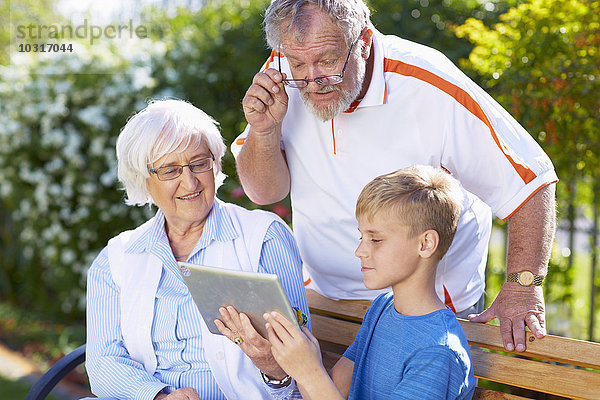 Enkel und Großeltern mit digitalem Tablett im Park