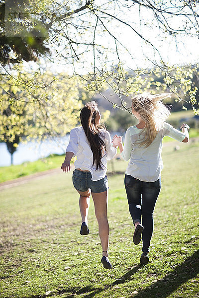 Zwei Freundinnen  die zusammen in einem Park laufen