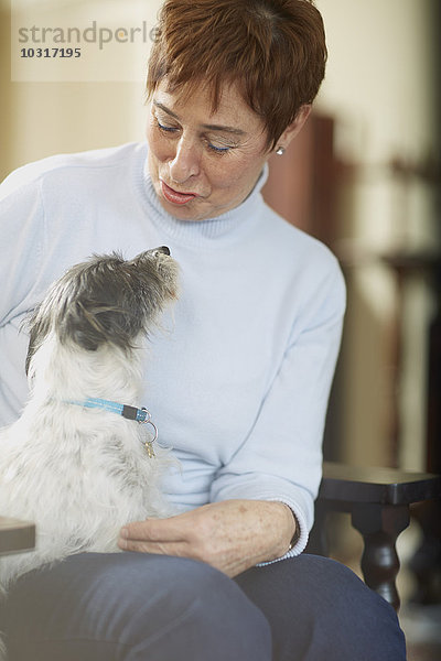 Glückliche Seniorin mit Hund zu Hause