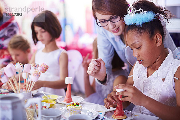 Mädchen beim Garnieren von Süßigkeiten auf einer Geburtstagsfeier