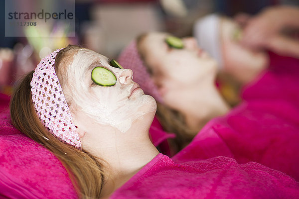 Mädchen auf einer Schönheitsfarm mit Gurkenmasken