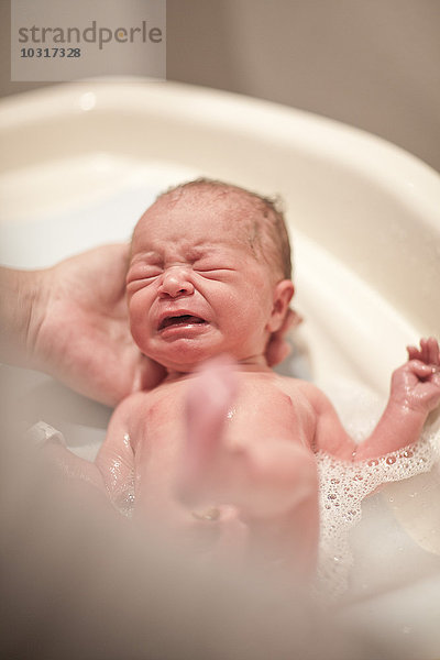 Neugeborenes Baby wird gebadet