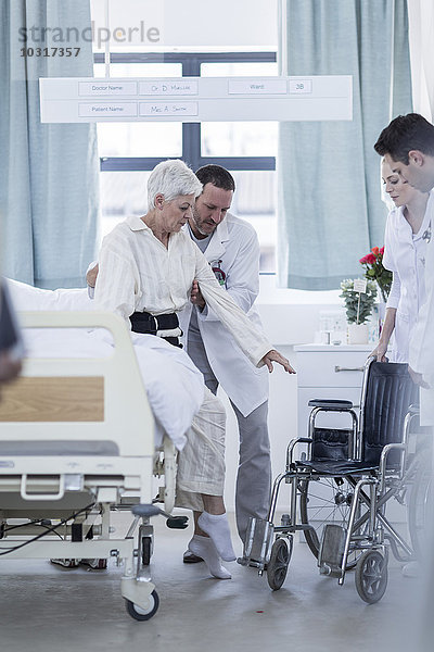 Arzt und Personal helfen Patienten mit Rollstuhl im Krankenhaus