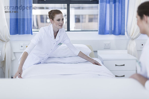 Zwei Krankenschwestern machen das Bett des Patienten