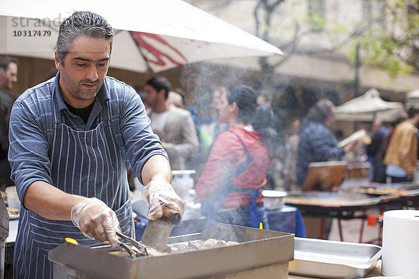Mann grillt Fleisch auf dem Stadtmarkt