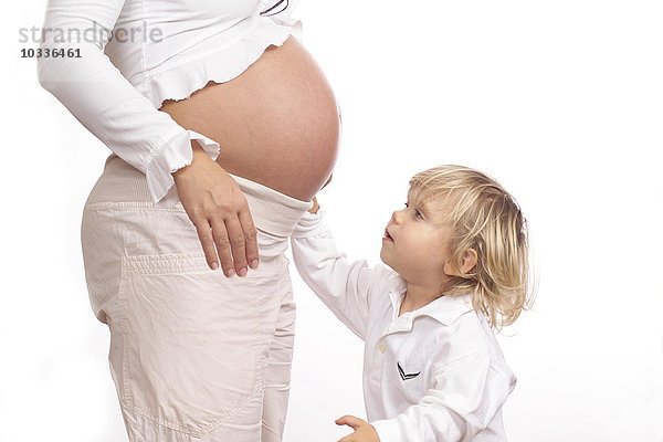 Kind berührt den Bauch einer schwangeren Frau