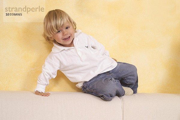 Kind sitzt auf einem Sofa und lacht