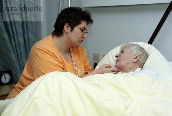 Krankenschwester am Bett einer älteren Frau - Betreuung von demenzkranken Patientinnen