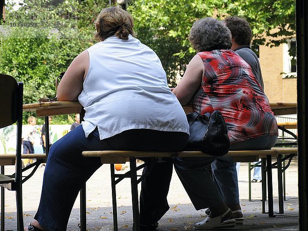zwei übergewichtige Frauen sitzen an einem Tisch in der Natur