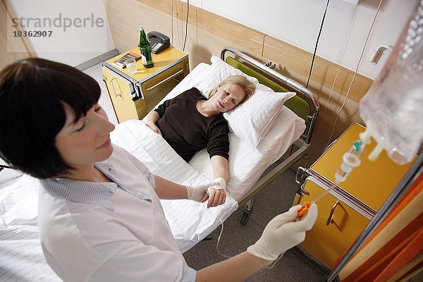 Krankenschwester legt eine Infusion für einen Patienten in einem Krankenhaus an.