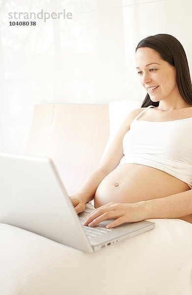 Schwangere Frau an einem Laptop