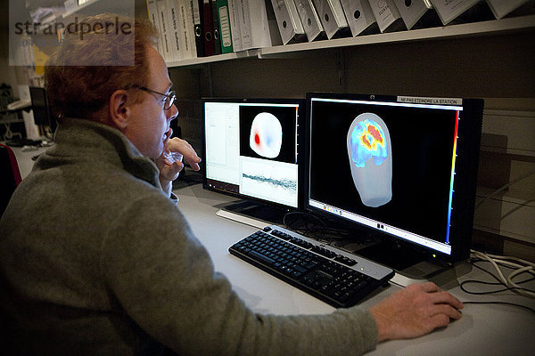 Reportage im Forschungszentrum für Neuroimaging im Krankenhaus Pitie Salpetriere in Paris  Frankreich. Plattform für Magnetoenzephalographie (MEG). Mit der MEG werden Schwankungen im Magnetfeld des Gehirns bei verschiedenen Arten von Hirnaktivitäten festgestellt. Sie dient der Untersuchung normaler und abnormaler Gehirnfunktionen. Die Aufzeichnung des von neuronalen Strömen erzeugten Magnetfelds erfordert hochempfindliche Sensoren  so genannte SQUIDs (Superconducting Quantum Interference Device). Die 306 Sensoren  die über 102 Bereiche verteilt sind  ermöglichen es  sowohl nahe als auch ferne Magnetfelder zu messen und die tiefen Strukturen des Gehirns zu sehen. Denis Schwartz betrachtet die Ergebnisse eines gesunden Patienten  der visuell stimuliert wurde. Das rechte Bild kombiniert einen MRT-Scan mit dem MEG.