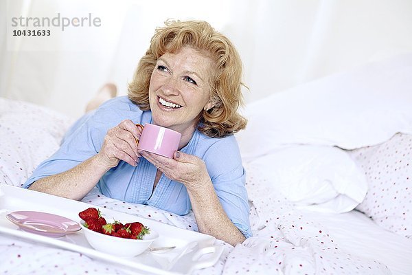 MODELL FREIGEGEBEN. Frau beim Frühstück im Bett.